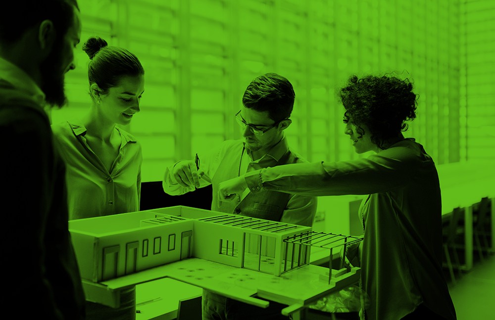 Group of young architects with model of a house standing in office, talking.